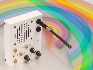Portable recorder/looper on its side with a rainbow background behind it. White with knobs and wooden buttons, a large speaker grill, and a gooseneck mic protruding perpendicular to the front panel.