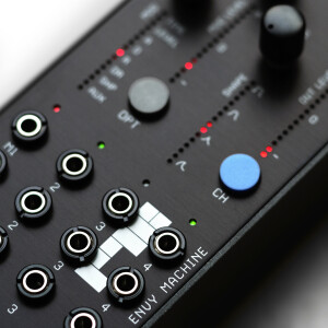 Close-up, angled view of Envy Machine, showing jacks, push-button selectors, LED indicators for modes, and tall, sleek encoders.