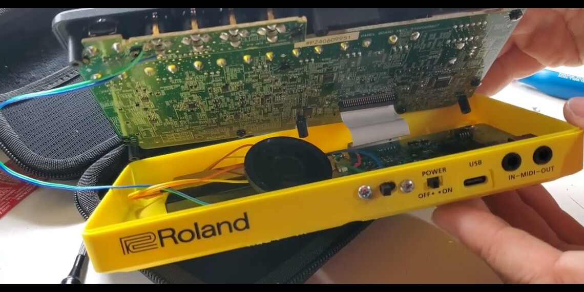 The yellow plastic case of a Roland P-6 pocket drum machine opened up, revealing the factory PCB board and mods with speaker and amplifier circuit.