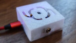 Therminator, with a curvy abstract glyph of a box with cables and a dot in the center engraved into the 3D-printed case, USB-C and jack connections