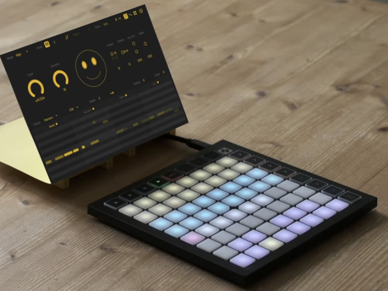 Virtual rendering of the Sting UI with knobs, piano roll view, and smiley face, angled next to a Novation Launchpad controller with light-up grid.